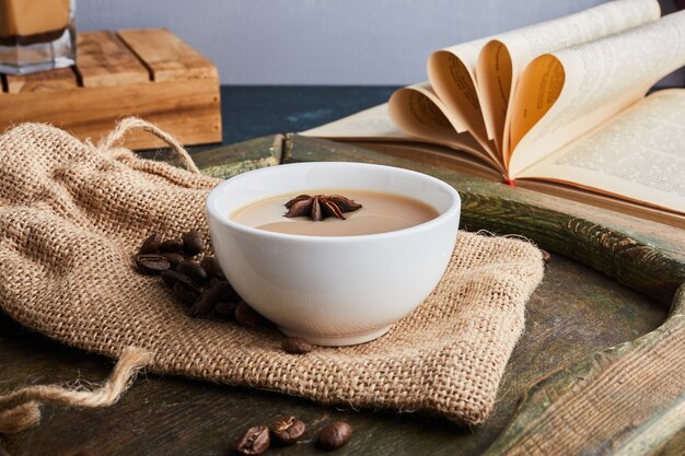 A cup of coffee with beans on burlap.