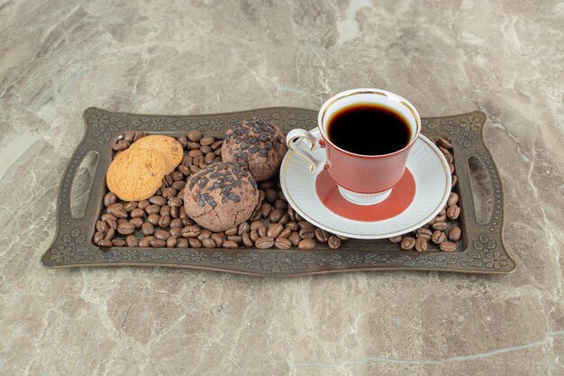 Cup of coffee with beans and cookies on plate