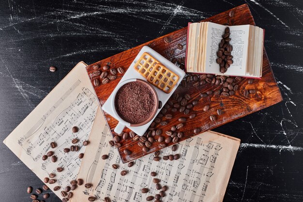 A cup of coffee with beans and cookies.