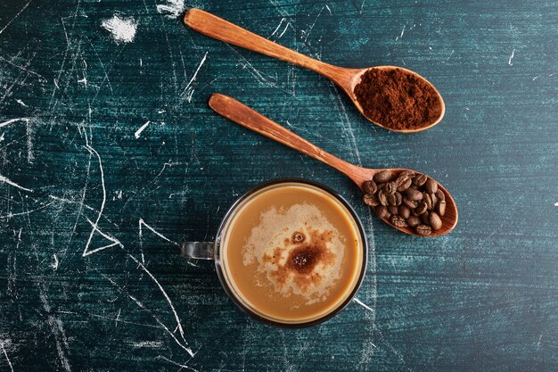 A cup of coffee with beans and powder. 