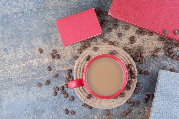 大理石の背景に本とコーヒー豆とコーヒーのカップ。高品質の写真