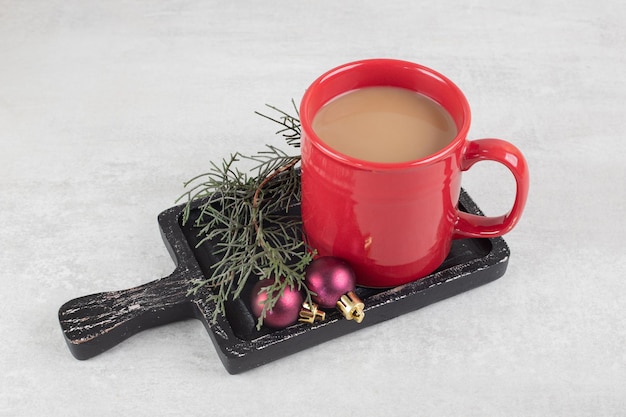 Cup of coffee with Christmas ornaments on dark board