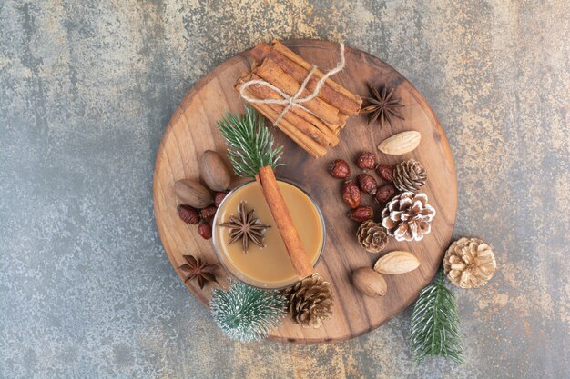 Cup of coffee with cinnamon sticks and pinecones on wooden plate. High quality photo