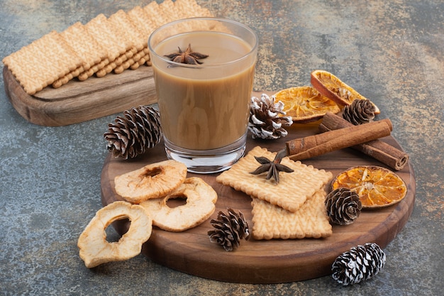 木の板にシナモンスティックと松ぼっくりとコーヒーのカップ。高品質の写真