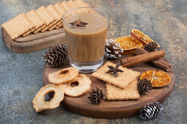 Cup of coffee with cinnamon sticks and pinecones on wooden plate. High quality photo