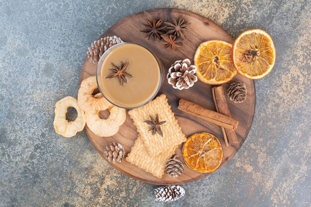 Cup of coffee with cinnamon sticks and pinecones on wooden plate. High quality photo