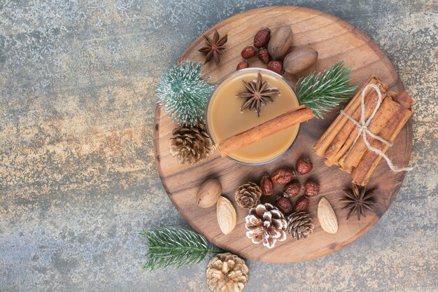 Cup of coffee with cinnamon sticks and pinecones on wooden plate. High quality photo