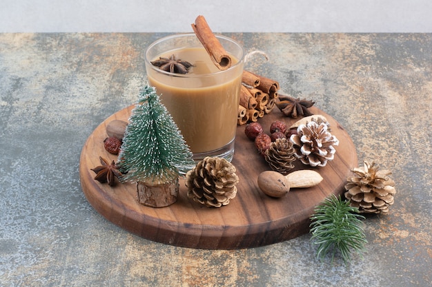 Cup of coffee with cinnamon sticks and pinecones on wooden plate. High quality photo