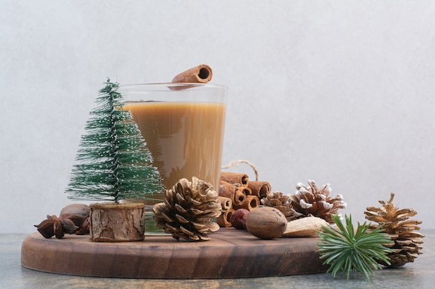 Tazza di caffè con bastoncini di cannella e pigne nelle quali sul piatto di legno. foto di alta qualità