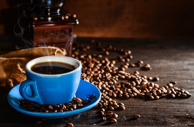 Cup of coffee with coffee beans and grinder background