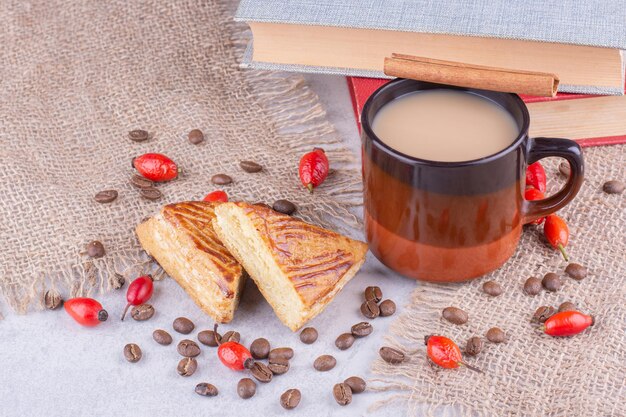 Cup of coffee with coffee beans and pastries on burlap. High quality photo