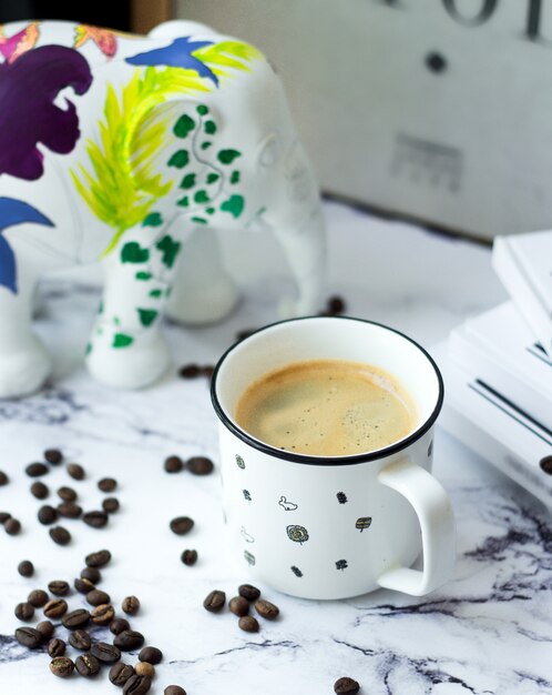 A cup of coffee with coffee beans on table