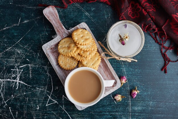 A cup of coffee with cookies in a tray, top view.