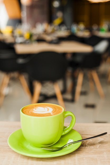 Free photo cup of coffee with creative latte art on wooden table at cafeteria