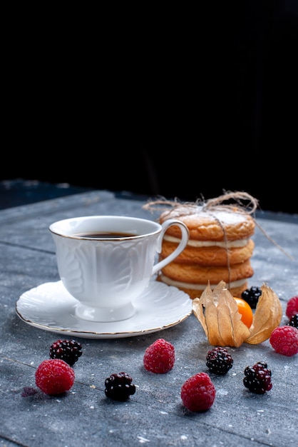 Tazza di caffè con diversi frutti di bosco e biscotti sandwich su grigio, bevanda al caffè di frutti di bosco