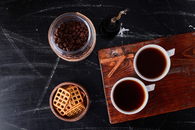 Cup of coffee with flavour cinnamons and cookies.