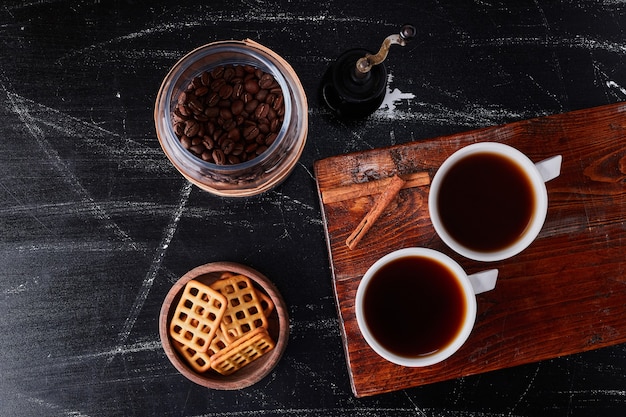 Cup of coffee with flavour cinnamons and cookies.