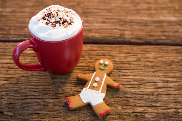 Free photo cup of coffee with foam and cinnamon on a table and a cookieman