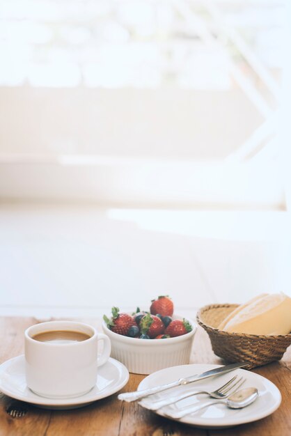 新鮮な果実と木製の背景の皿にカトラリー一杯のコーヒー