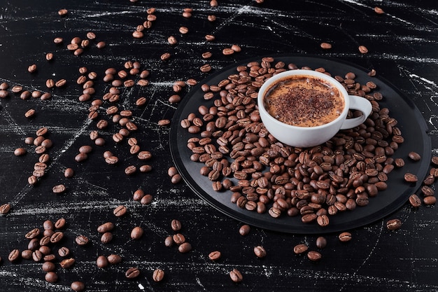 Foto gratuita tazza di caffè con grani intorno.