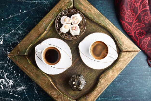 A cup of coffee with lokum in a wooden tray. 