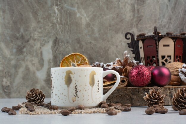 Cup of coffee with pinecones and Christmas balls on wooden plate . High quality photo