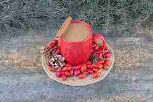 Foto gratuita una tazza di caffè con cinorrodi e pigne su fondo marmo. foto di alta qualità