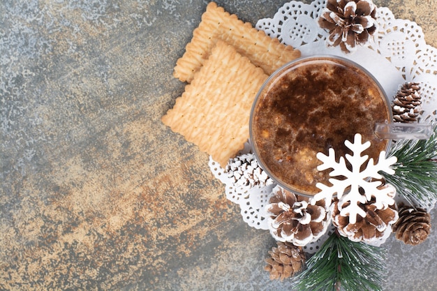 Чашка кофе с вкусными крекерами и шишками на мраморном фоне. Фото высокого качества