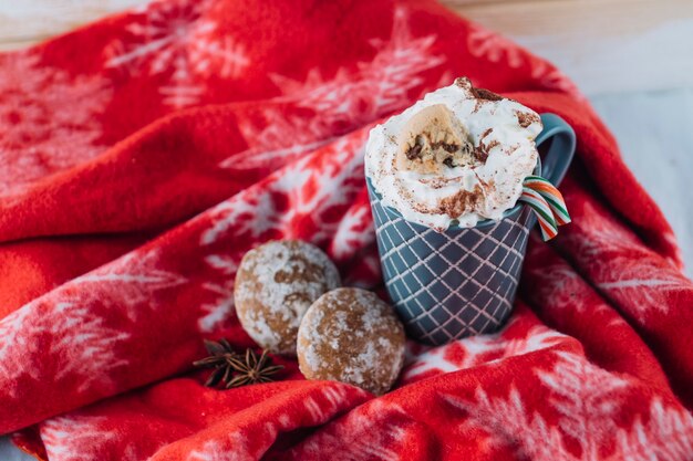 Cup of coffee with whipped cream on blanket 