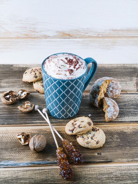 Cup of coffee with whipped cream and cookies on table 