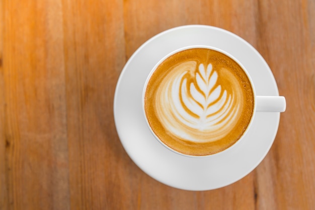 Cup of coffee with a wisp of wheat drawn in the froth seen from above