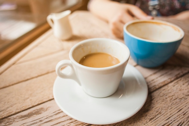 Cup of coffee on wooden table in cafeteria