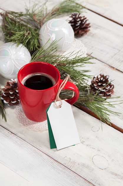 cup of coffee on the wooden table with a empty  blank price tag and Christmas decorations.