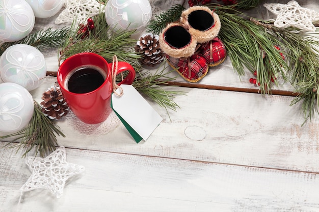 cup of coffee on the wooden table with a empty  blank price tag and Christmas decorations.