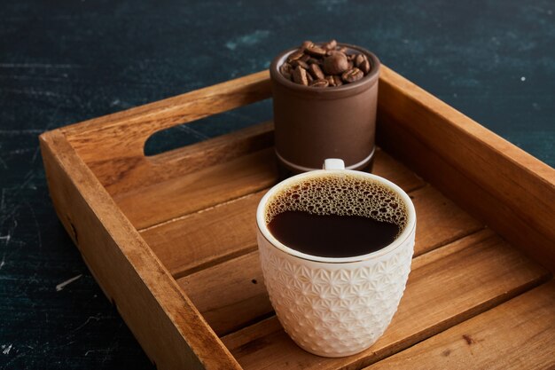 Una tazza di caffè in un vassoio di legno.