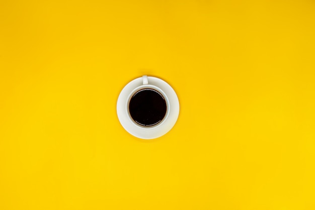 黄色の表面にコーヒー1杯