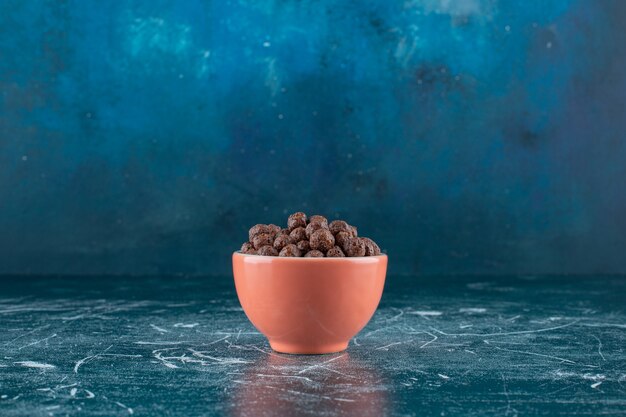 Чашка кукурузных шариков на синем фоне. Фото высокого качества