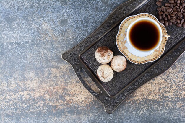 A cup of dark coffee with cookie on dark board. High quality photo