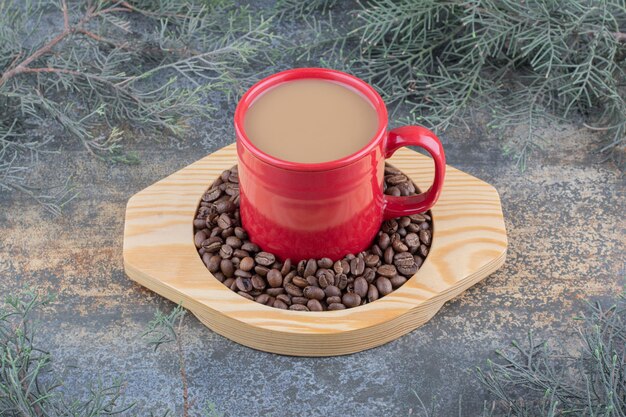 A cup of delicious coffee with coffee beans on wooden board. High quality photo