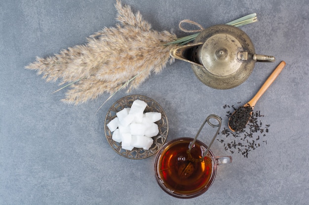 Una tazza di tè delizioso con bollitore antico e zucchero.