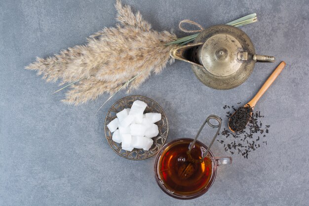 A cup of delicious tea with ancient kettle and sugar .