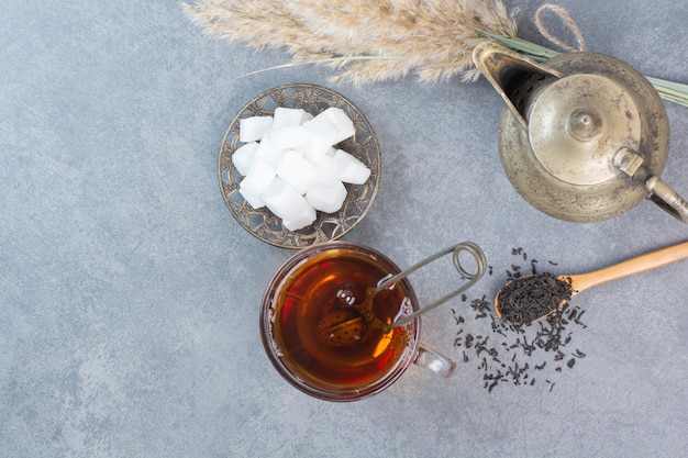 A cup of delicious tea with ancient kettle and sugar 