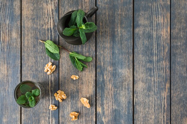 Cup of drink near pitcher, plant twigs and nuts on table