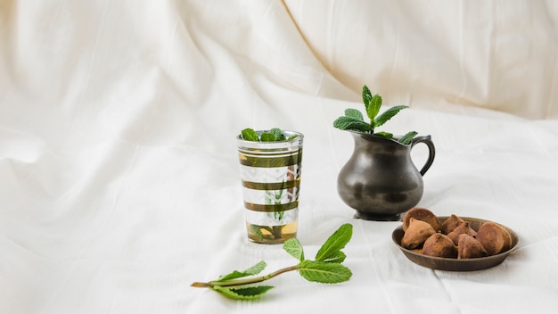 Cup of drink near pitcher and truffles