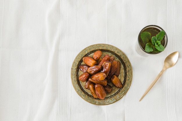 Cup of drink near spoon and dried fruits