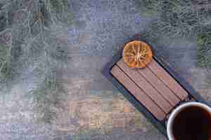 Free photo cup of espresso, stick biscuits and coffee beans on black plate.