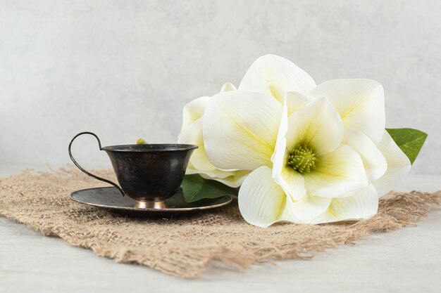 Чашка эспрессо и белые цветы на мешковине