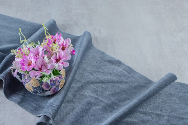 Чашка цветов на куске ткани, на белом фоне. Фото высокого качества