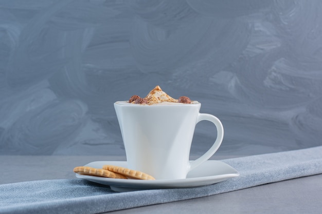 돌 테이블에 거품 뜨거운 커피와 비스킷의 컵.