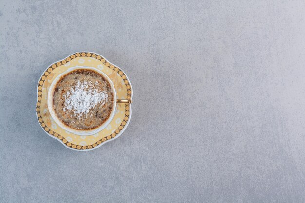 Cup of foamy hot coffee placed on stone table.